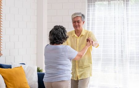 asian seniors couple enjoy dancing in living room at home.aging at home conceptの写真素材