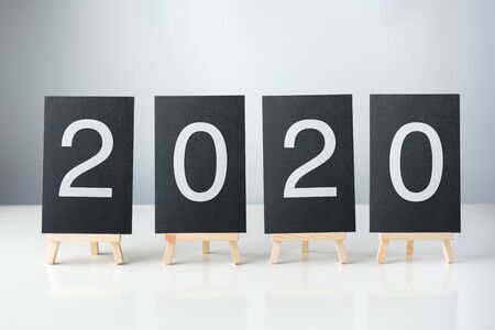 happy new year 2020 with blackboard on white table and grey background. holiday celebrationの写真素材