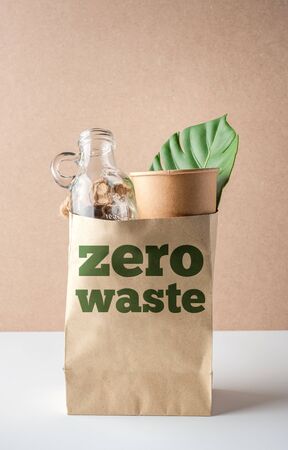 zero waste  and plastic free concept. grocery bag with glass bottle, paper cup and leaf on white table. eco friendlyの写真素材