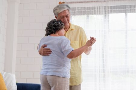 asian seniors couple enjoy dancing in living room at home.aging at home conceptの写真素材