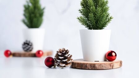 christmas tree with pine cone and decor xmas ball on white table and marble tile wall background.clean minimal simple style.holiday still lifeの写真素材