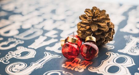Christams gold pine conre and red glass ball decoration on vintage type pattern table background.holiday greeting card with copy spaceの写真素材