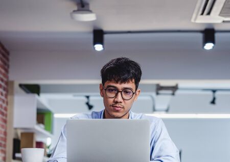 asian businessman woking with laptop and paper work on desk  at office.digital workflow online business lifestyle conceptの写真素材
