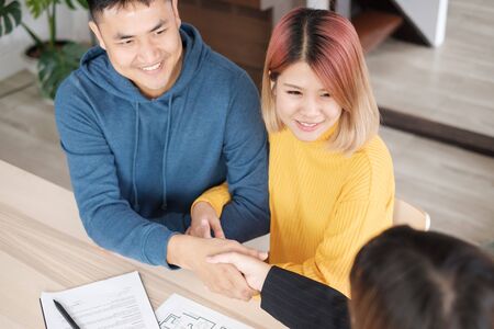 Asian happy couple getting key and handshake with realtor agent with smiling face at new home.buying new house real estateの写真素材