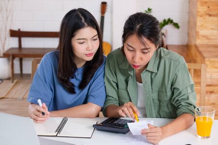 Asian lesbain couple together calculate home budget with paper bill in new house at table in kitchen の写真素材