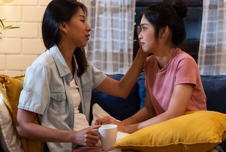 Asian lesbian couple comforting girlfriend when she sad with love and care in night time at homeの写真素材
