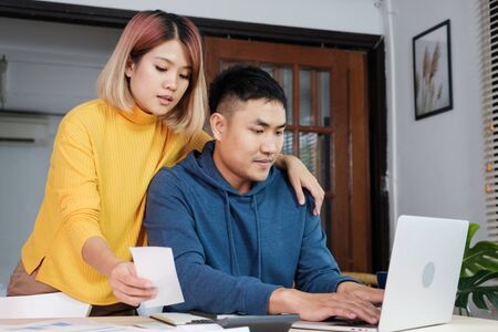 Asian couple list home financial bill budget on table in kitchen at new house.family expenseの写真素材