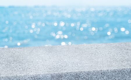 summer background.Empty diagonal grey pebble stone table with blur sea and sky boekh background,banner mockup template for display of productの写真素材