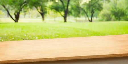 Tropical spring background.Empty diagonal wooden table with blur tree in park boekh background,banner mockup template for display of productの写真素材