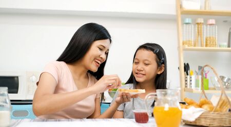 Mother and preteen daughter make sandwich togerther in kitchen at home.family happy time.quarantine activity when outbreak of coronavirusの写真素材