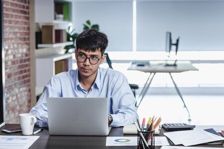 asian businessman woking with laptop and paper work on desk  at office.digital workflow online business lifestyle conceptの写真素材