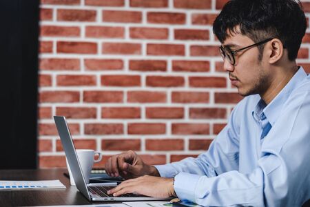 asian businessman woking with laptop and paper work on desk  at office.digital workflow online business lifestyle conceptの写真素材