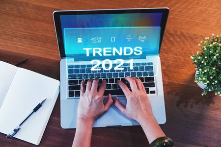Trends for 2021 augmented reality (AR) floating screen with hand typing keyboard on laptop and notebook on wood table,Digital Business disruption or marketing trending.digital transformationの写真素材