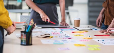 Close up ux developer and ui designer brainstorming about mobile app interface wireframe design on table with customer brief and color code at modern office.Creative digital development agency.panningの写真素材