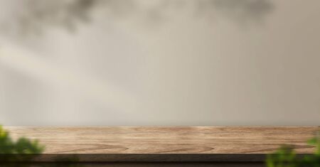 wood table backgorund with sunlight window create leaf shadow on wall with blur indoor green plant foreground.panoramic banner mockup for display of product,warm tone lightsの写真素材