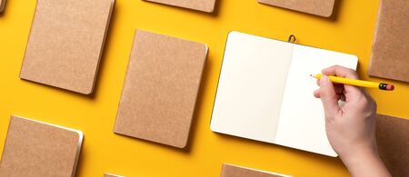 content marketing concept,.top view of hand writing on open notebook align with kraft paper book in pattern on yellow table background.mockup for advertise content onlineの写真素材