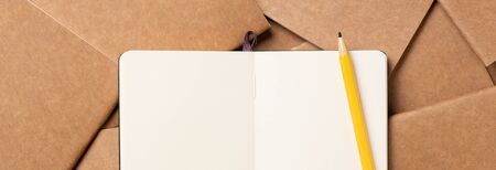 open notebook with pencil on brown kraft notebook disorder alignment on table background.mokcup template for diaplay content or design.content marketing conceptの写真素材