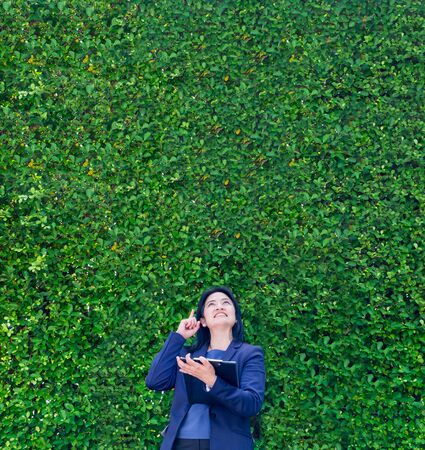 ecology buseinss woman wear suit thinking at green leaf wall with spaceの写真素材