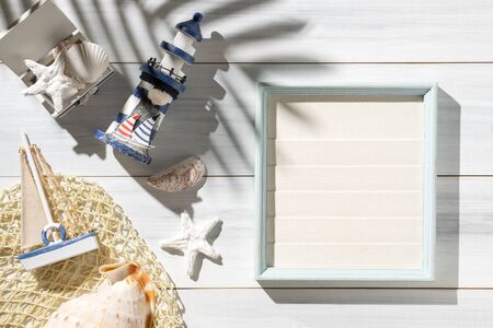 Top view summer rustic picture frame and lighthouse,seashell decorate on white wooden table with sunlight shadeの写真素材