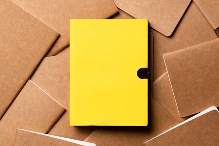 yellow notebook on brown kraft notebook disorder alignment on table background.mockup template for display content or design.content marketing conceptの写真素材