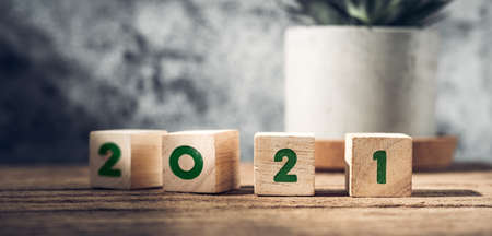 2021 happy new year on wood block on wood table and concrete wall with sunlight from window.hope new...