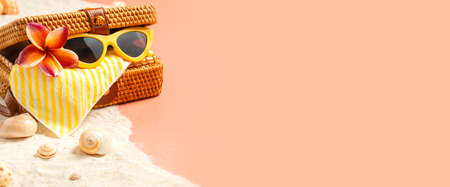summer sand beach with wicker bag and sunglasses on peach vintage color background.vacation banner mockupの写真素材