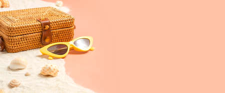 summer sand beach with wicker bag and sunglasses on peach vintage color background.vacation banner mockupの写真素材