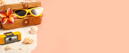 summer sand beach with wicker bag and sunglasses on peach vintage color background.vacation banner mockupの写真素材