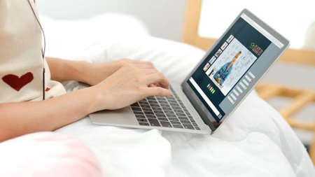 Asian female student video conference with teacher and friends using e-learing app on laptop computer at home.woman lying down on carpet.new normal learning online lifestyleの写真素材