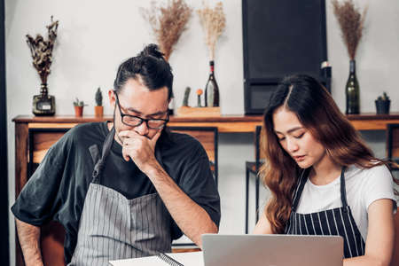 Asian barista man and woman serious meeting with laptop about business plan in coffee shopの写真素材