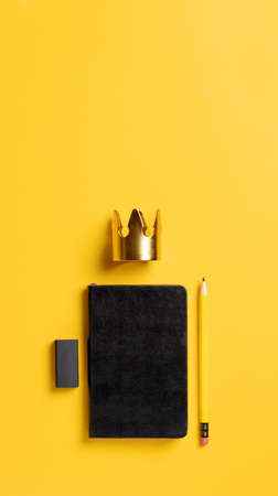 content is king for online marketing concept.top view of black notebook with golden crown and pencil on yellow table background,vertical banner for advertising on mobile mediaの写真素材