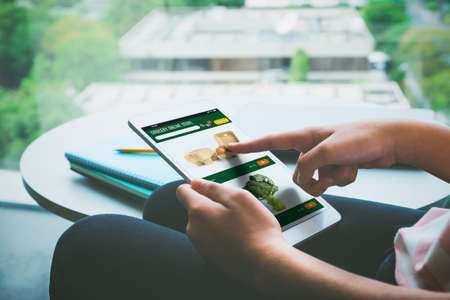 close up hand of woman order grocery online store with tablet and pay contactless at apartment.new normal digital lifestyle with technologyの写真素材