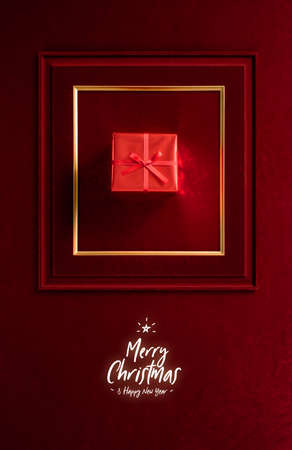 Merry Christmas and happy new year glowing with Red Christmas gift in picture frame on velvet red felt fabric wall.winter holiday backgroundの写真素材