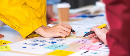 Close up hand ux developer and ui designer brainstorming about mobile app interface wireframe design on table at modern office.Creative digital development agencyの写真素材