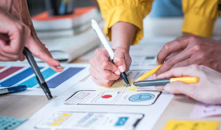 Close up hand ux developer and ui designer brainstorming about mobile app interface wireframe design on table at modern office.Creative digital development agencyの写真素材