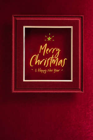 Merry Christmas and happy new year glowing with star in picture frame on velvet red felt fabric wall.winter holiday backgroundの写真素材