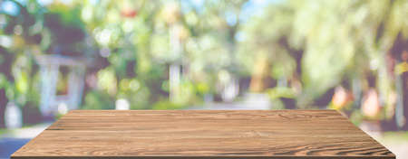spring background.Empty brown wooden table with blur tropical  tree in garden boekh background,banner mockup template for display of productの写真素材