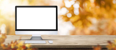 Autumn background.Blank desktop computer on rustic wood table with blur forest tree with...