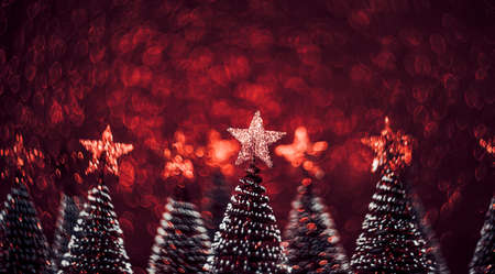 Christmas tree with star on red glitter swirly sparkling lights festive bokeh background.new year holiday greeting cardの写真素材
