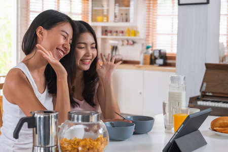 Happy asian couple lesbian getting marriage and showing ring to friend infront of tablet with video call.LGBTQ lifestyle conceptの写真素材