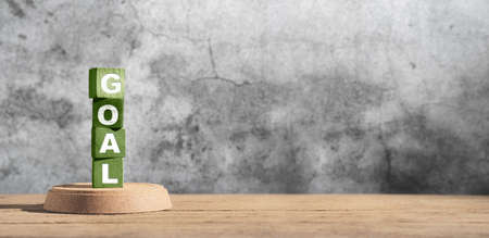 new year green goal word on wood block on wood table with concrete wall background.banner space for display of design or content of business resolutionの写真素材