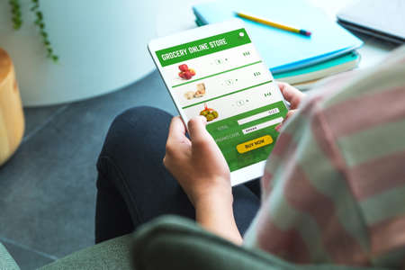 Close up woman hand holding grocery online store mobile apps order food online at home.stay at home conceptの写真素材