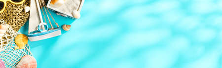 Tropical summer beach sea accessories objects,sunglasses,green straw bag,sailing and seashell over blue turquoise background banner  with sunlight .の写真素材