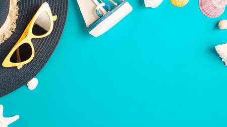 Tropical summer beach sea accessories objects,sunglasses,green straw bag,sailing and seashell over blue turquoise backgroundの写真素材