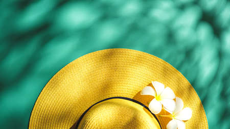 Yellow straw hat over green turquoise background with sunlight ,Minimal summer beach seaの写真素材