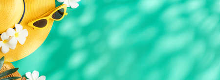 Tropical summer yellow straw hat and singleness on turquoise background with sunlight and shade.banner mockup space for product display advertiseの写真素材