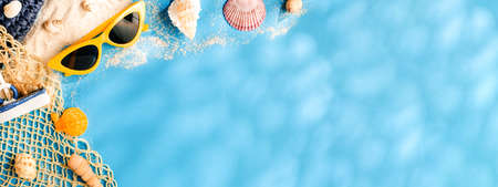 Tropical blue summer sand beach sea with  accessories objects,sunglasses,straw hat and seashell on blue pastel background banner with sunlightの写真素材
