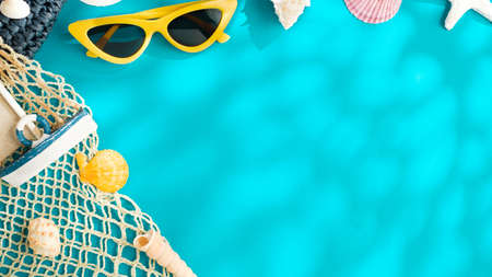 sunny day summer beach sea accessories,sunglasses,brown hat and seashell over blue background banner with sunlightの写真素材