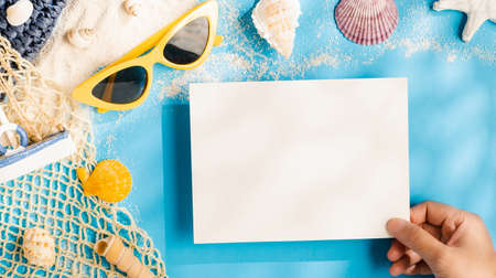 summer sunlight concept.hand holding blank paper on beach accessory on blue sea backgroundの写真素材