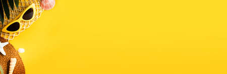 Yellow hot summer with straw hat and sunglasses on vibrant yellow backgroundの写真素材